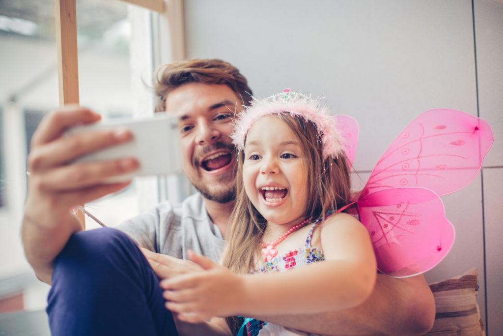 Kummilapsi on pukeutunut keijukaiseksi, ja kummi ottaa selfien hänen kanssaan.