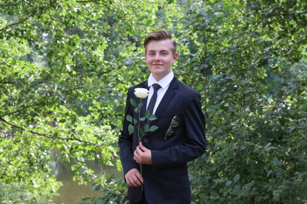 Anton poseeraa konfirmaatiopäivänä kesäisessä maisemassa